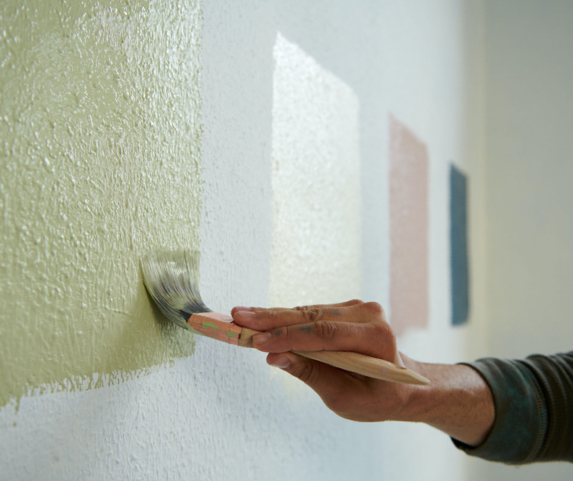 personne peignant plusieurs échantillons de couleur sur le mur pour choisir la couleur de la peinture 